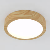 A round ceiling light with a smooth, light wood frame and a bright white diffuser, mounted on a white ceiling.