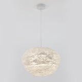 A modern pendant light fixture with a round, fluffy lampshade made of layered, white feather-like material, suspended from the ceiling by a thin, straight cord.