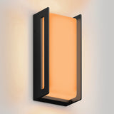 A modern wall sconce with a black rectangular frame and a glowing, frosted orange light panel mounted on a white wall.