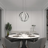 Modern dining room with a round marble table set for four, gray upholstered chairs, a sculptural LED pendant light, a large green plant, and minimalist white décor with subtle wall accents.