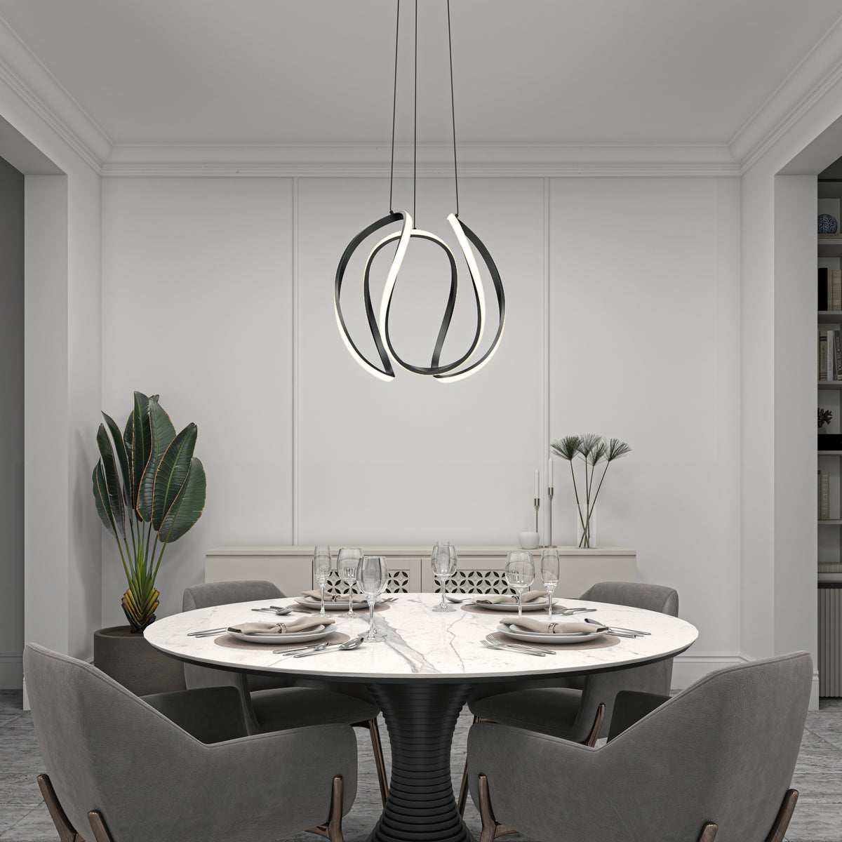 A modern dining room features a round marble table for four, grey chairs, a Vivaldi Big LED pendant light by Artika, a large potted plant, and minimalistic decor in neutral tones.