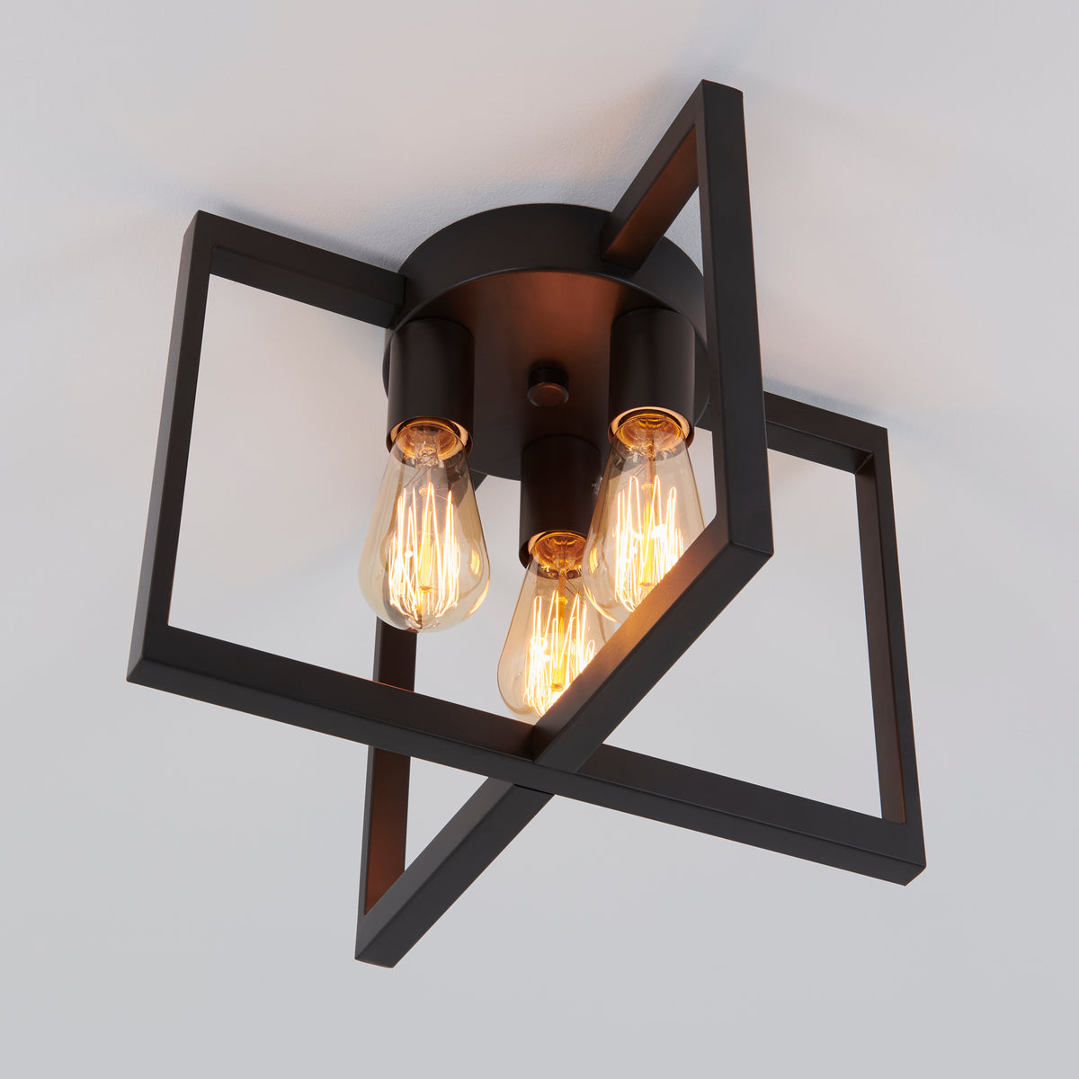 A modern ceiling light fixture with three exposed Edison bulbs, featuring intersecting black square metal frames against a white ceiling.