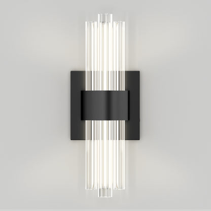 The Artika Dorado LED contemporary wall sconce 3 CCT features vertical tubular glass lights on a rectangular black metal base, mounted on a light gray wall, providing a soft, even glow.
