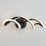 A modern wall sconce with three curved, black arms featuring integrated warm LED lighting, arranged asymmetrically and mounted on a circular black base against a light gray wall.