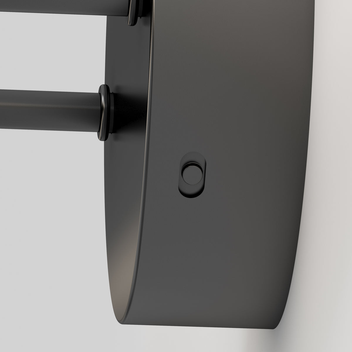 Close-up view of a modern, black, wall-mounted cylindrical light fixture attached to a white wall, featuring a small round button on its side.