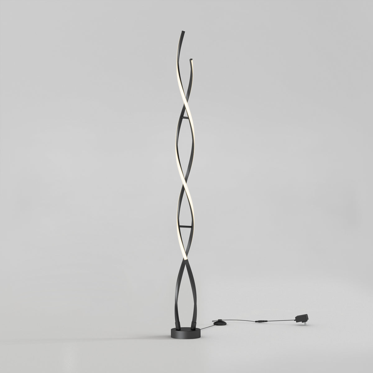 The Artika Swirl modern LED floor lamp features two black intertwining curved stems, one emitting soft white light. It stands on a round base with a visible plug-in cord, set against a plain light gray background.