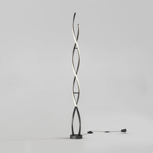 The Artika Swirl modern LED floor lamp features two black intertwining curved stems, one emitting soft white light. It stands on a round base with a visible plug-in cord, set against a plain light gray background.