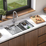 Modern kitchen sink with a pull-down faucet, built into a marble countertop. A wooden cutting board with figs, herbs, and a knife sits beside the sink near a window overlooking greenery.
