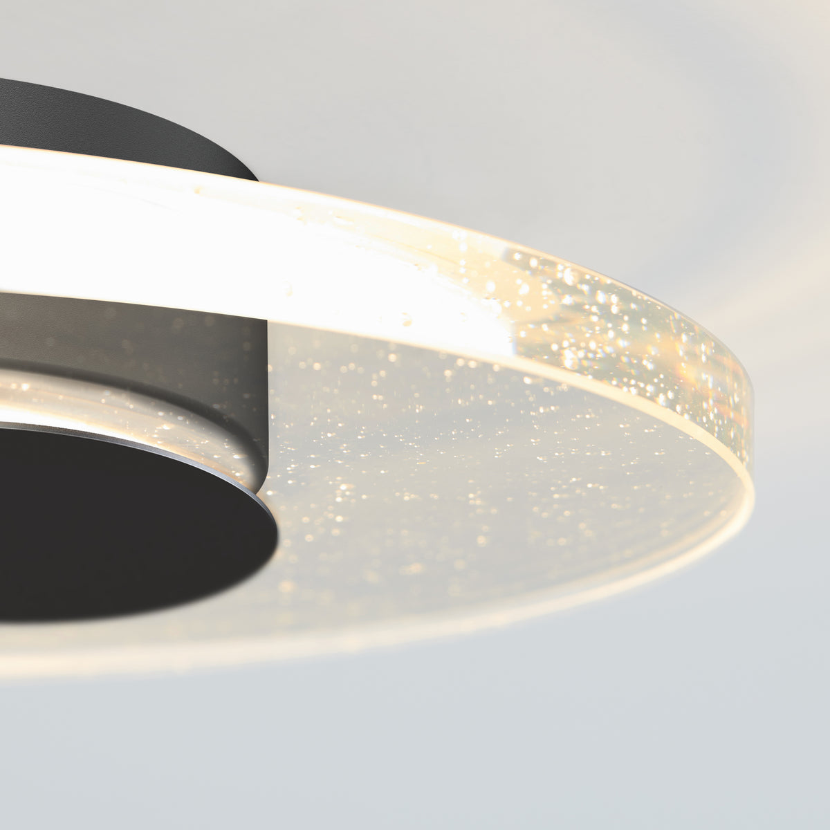 Close-up of Artikas Essence Disk LED flush mount, featuring a circular glowing rim and embedded bubbles that create a sparkling effect against a soft white background.