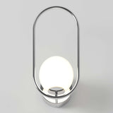 A modern wall sconce with a glowing white spherical bulb, surrounded by a sleek, oval-shaped chrome frame, mounted on a circular chrome base against a light gray background.