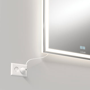 A white plug powers the Artika Aurea 24″x31″ anti-fog LED mirror, its glowing edges lighting a pale wall.
