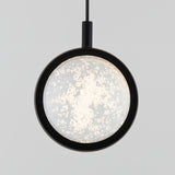 A modern pendant light with a circular, black frame and a glass center featuring bubble-like patterns, suspended by a black cord against a plain, light gray background.