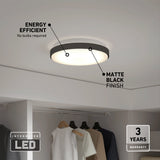 A round, matte black LED ceiling light is mounted above a closet with hanging clothes. Text highlights its energy efficiency, integrated LED, matte black finish, and 3-year warranty.