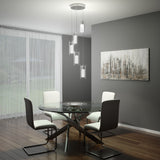 A modern dining room with a glass round table, four white and gray chairs, a hanging contemporary light fixture, abstract wall art, wooden floors, and sheer curtains revealing a green backyard.