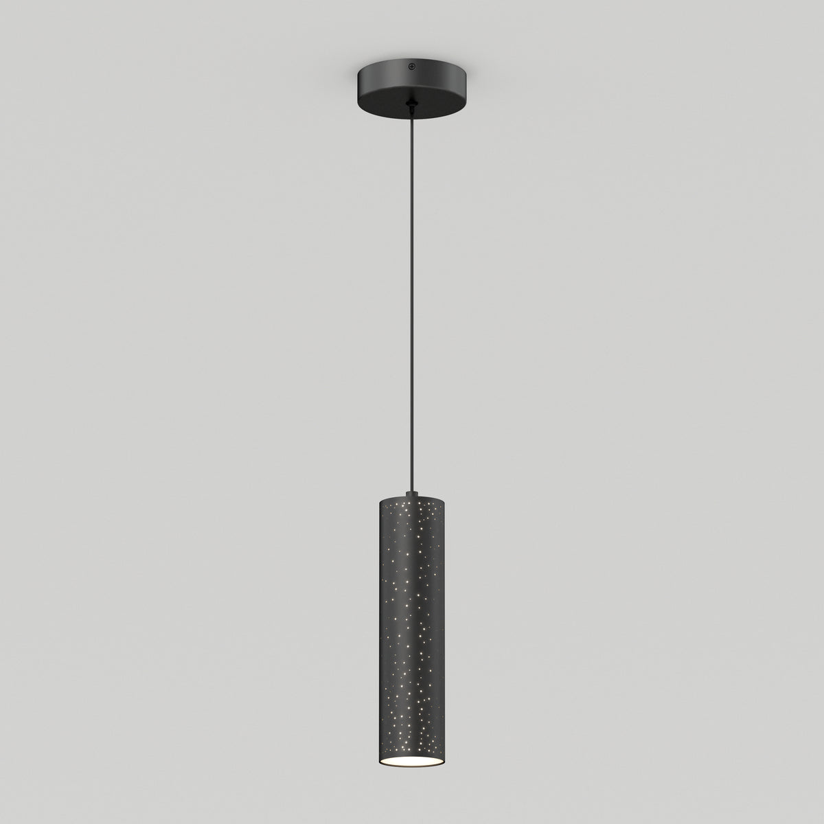 A modern black cylindrical pendant light hangs from the ceiling by a thin cord. The lampshade has small perforated holes, allowing light to shine through, and casts a subtle glow below against a plain white background.