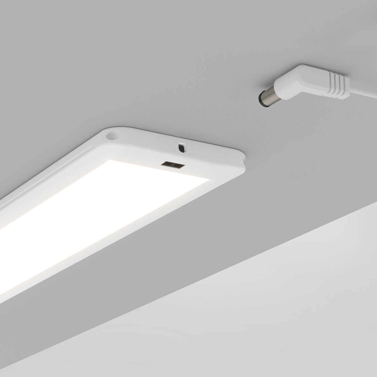 The Artika Maestro under cabinet LED light 3CCT is a rectangular white fixture mounted beneath a gray surface, with its power cable and connector plugged in.