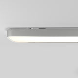A close-up view of a modern, rectangular ceiling light fixture with rounded edges, emitting a soft white glow against a plain, light gray ceiling.