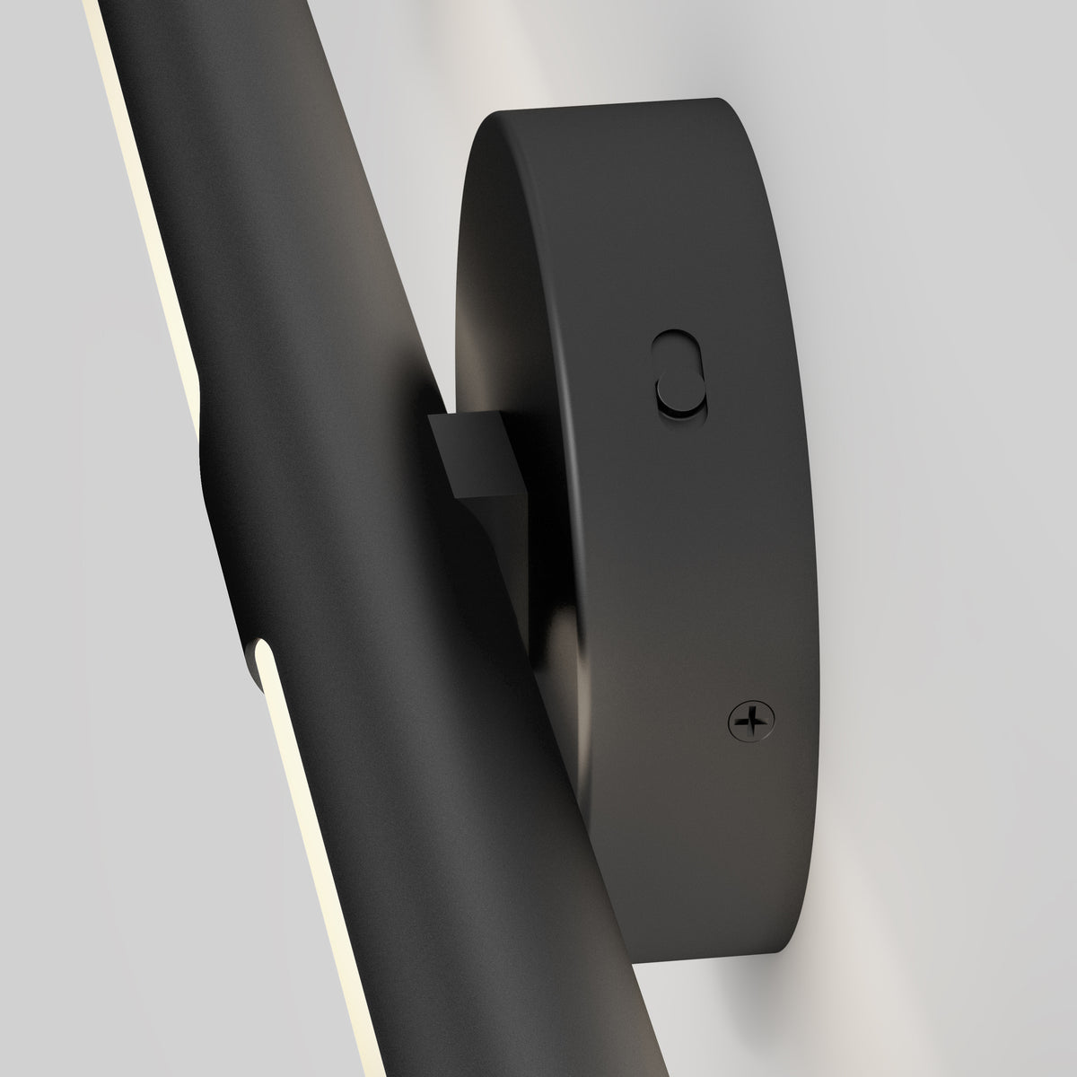 Close-up of a modern black wall-mounted light fixture with a cylindrical base and a sleek, angled light bar attached, against a plain white background.