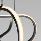 Close-up of a modern, curved LED light fixture with a black frame, glowing softly against a plain gray background. The design is minimalistic and contemporary.