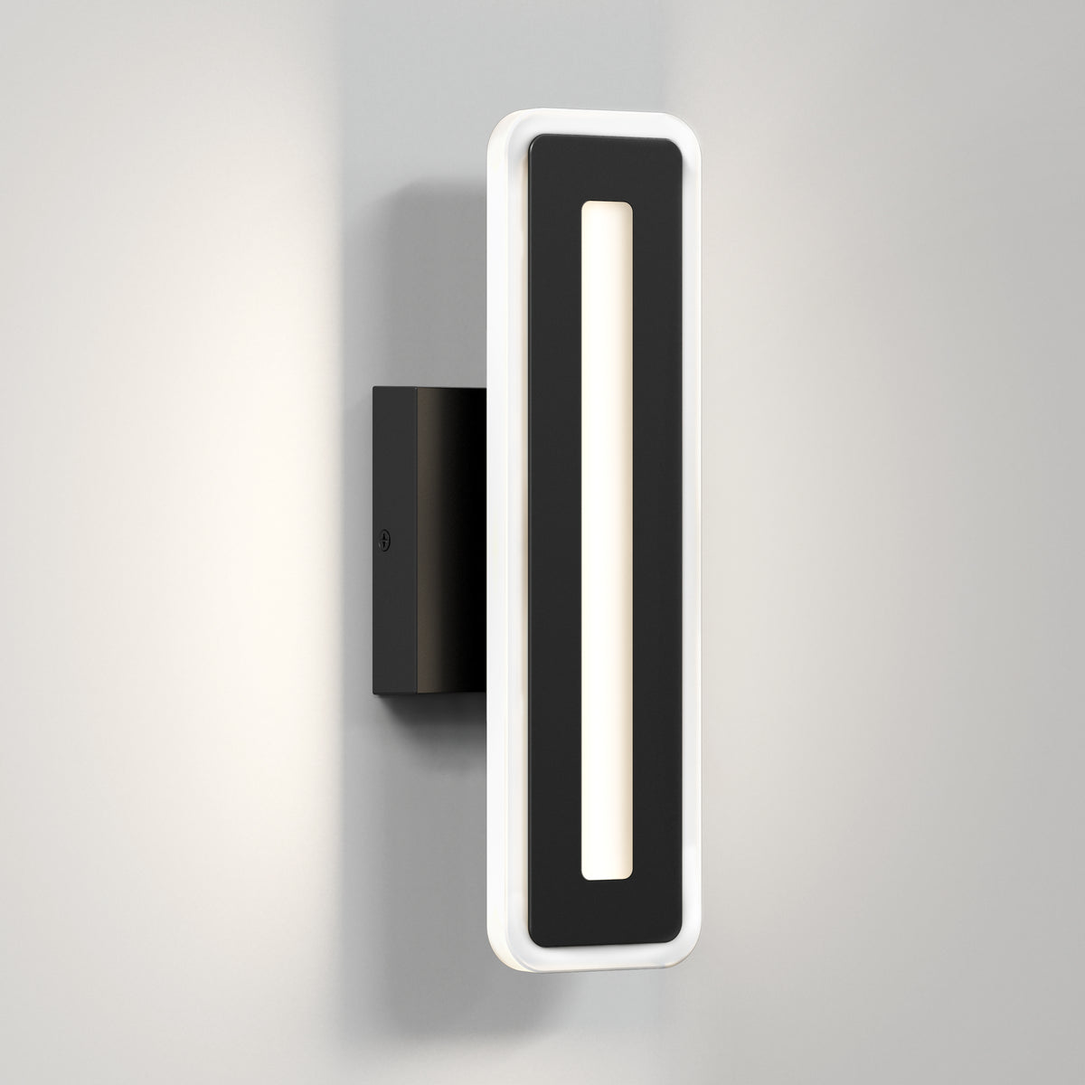 A modern black wall sconce with a rectangular design, featuring a central cutout and a white illuminated border, mounted on a light gray wall.