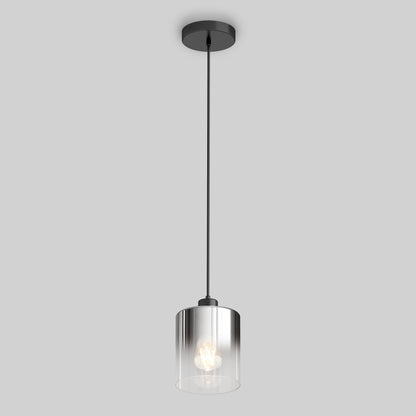 The Artika Haze pendant light glass features a cylindrical clear glass shade, black cord, and black ceiling mount. Against a plain gray background, the illuminated bulb is visible inside the modern fixture.