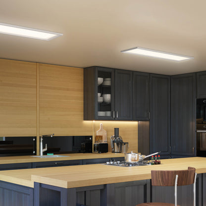 Modern kitchen with dark cabinets, light wood countertops, built-in appliances, a blender, and cups on the counter. Overhead illumination is provided by the Artika Sunray ultra thin LED light panel 3 CCT. A wooden chair sits at the island.