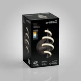 A black box with the Artika logo displays a modern wall light called “Chorus.” The light features a spiral LED design, energy information, and product details on the packaging. The background is light gray.