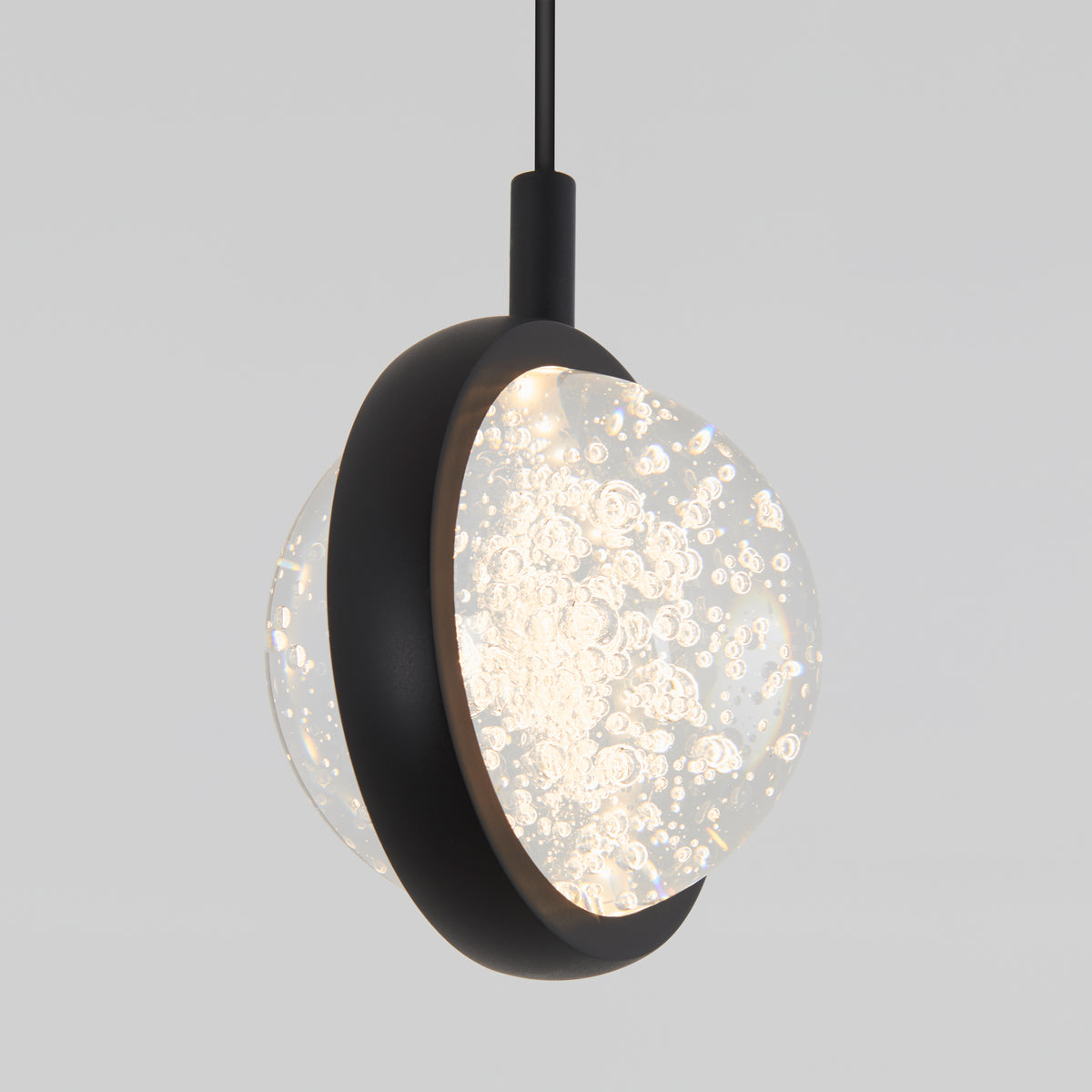 A modern pendant light with a black circular frame encasing a textured glass globe filled with bubbles, suspended from a black cord against a plain light gray background.