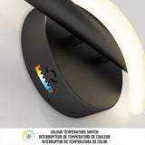 A close-up of a black wall-mounted light fixture with a curved LED bar and a visible color temperature switch, showing a label with a mountain graphic and color settings. Text below describes the switch in English and French.