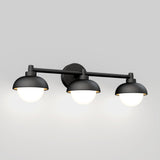 A black, wall-mounted light fixture with three dome-shaped shades, each housing a glowing round bulb, set against a plain light gray background.