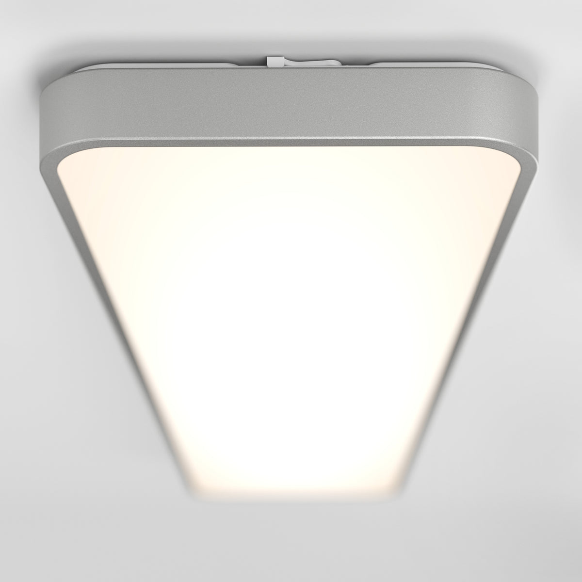 A modern, rectangular ceiling light fixture with rounded edges emits a bright, even white light against a plain white ceiling.