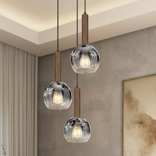 The Artika Ardel Spiral 3-Light Pendant without Bulbs features wooden stems and clear glass shades, bringing modern style and warm ambiance to rooms with beige walls, a large curtain, and framed artwork.