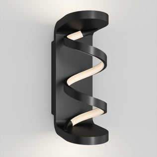 The Artika Swirl indoor-outdoor LED wall light features a black frame and spiral-shaped LED strip, mounted vertically on a white wall. Its sleek, modern design emits soft, diffused light for contemporary spaces.