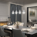 Elegant dining room with a set table, gray upholstered chairs, a modern chandelier of four glass pendant lights, a fireplace, floral centerpiece, and a view into a living area with a sofa and wall art.