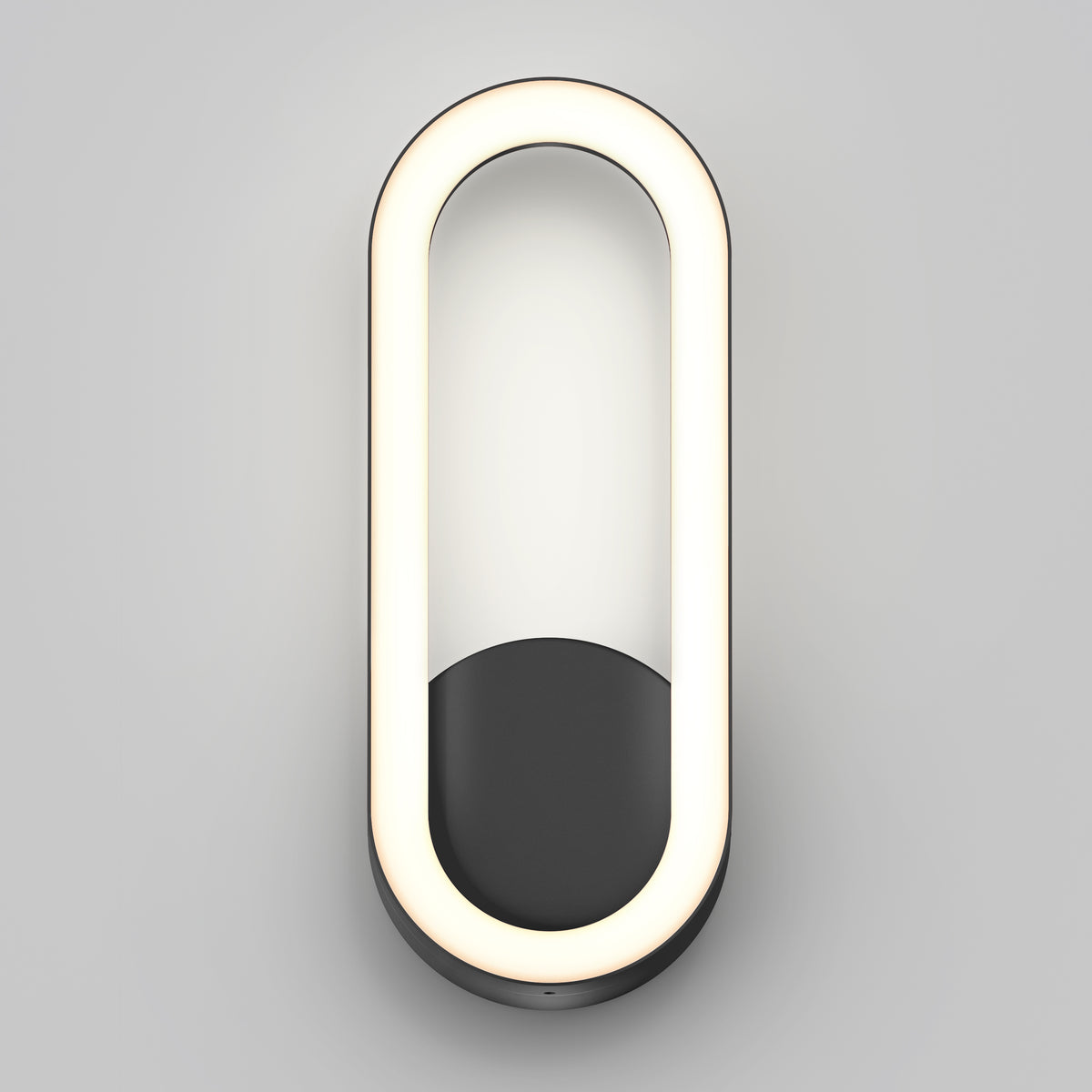 A modern, oval-shaped wall sconce with a black base and a continuous white LED light forming the outer edge, mounted on a light gray wall.