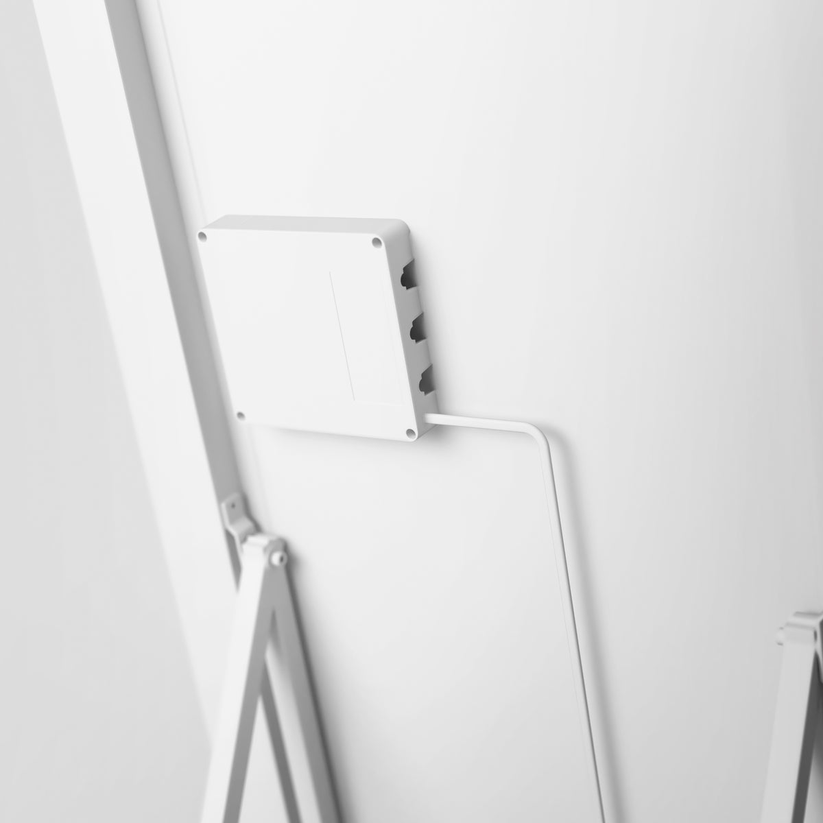 A close-up of a white electronic device mounted on a wall with a cable plugged into it, and a metal support structure visible on the left side.