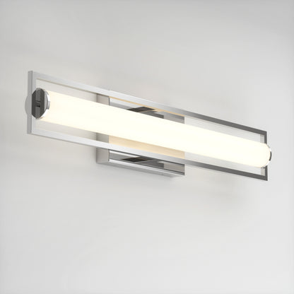 A modern wall-mounted light fixture with a sleek, rectangular chrome frame and a long, cylindrical frosted glass bulb, emitting a soft white glow against a plain white wall.