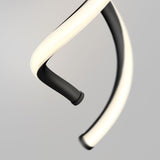 A close-up of a modern, spiral-shaped light fixture with a glowing white strip wound around a black curved structure, set against a plain, light grey background.