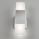 A modern wall sconce with a brushed metal rectangular center and two frosted white square light diffusers on the top and bottom, mounted on a light gray wall.