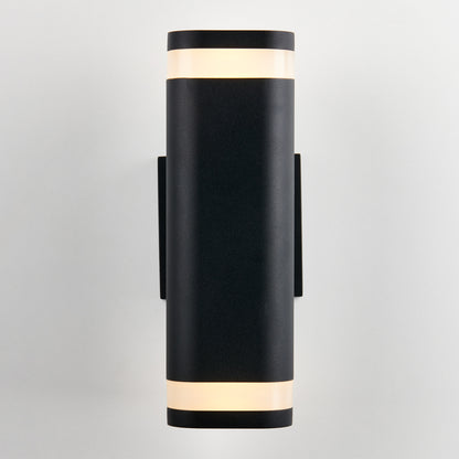 The Artika Mettle LED indoor-outdoor wall light is a modern black cylindrical sconce with frosted diffusers at the top and bottom, shown mounted vertically on a plain white wall.