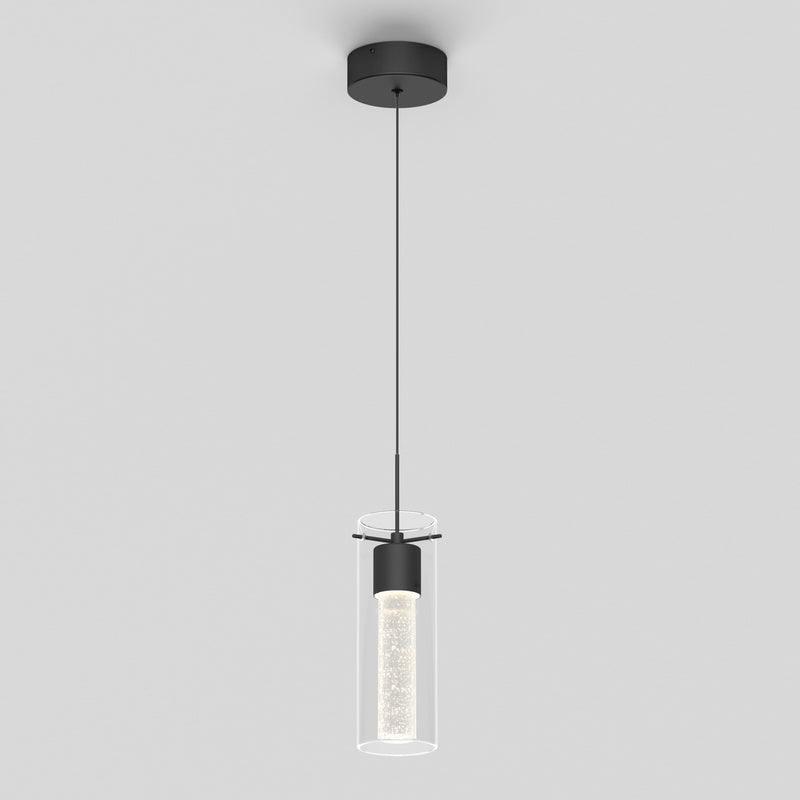 The Essence LED pendant light by Artika features a black ceiling mount, a cylindrical glass shade, and a slim black cord. The illuminated inner cylinder creates a sparkling effect for a modern look.