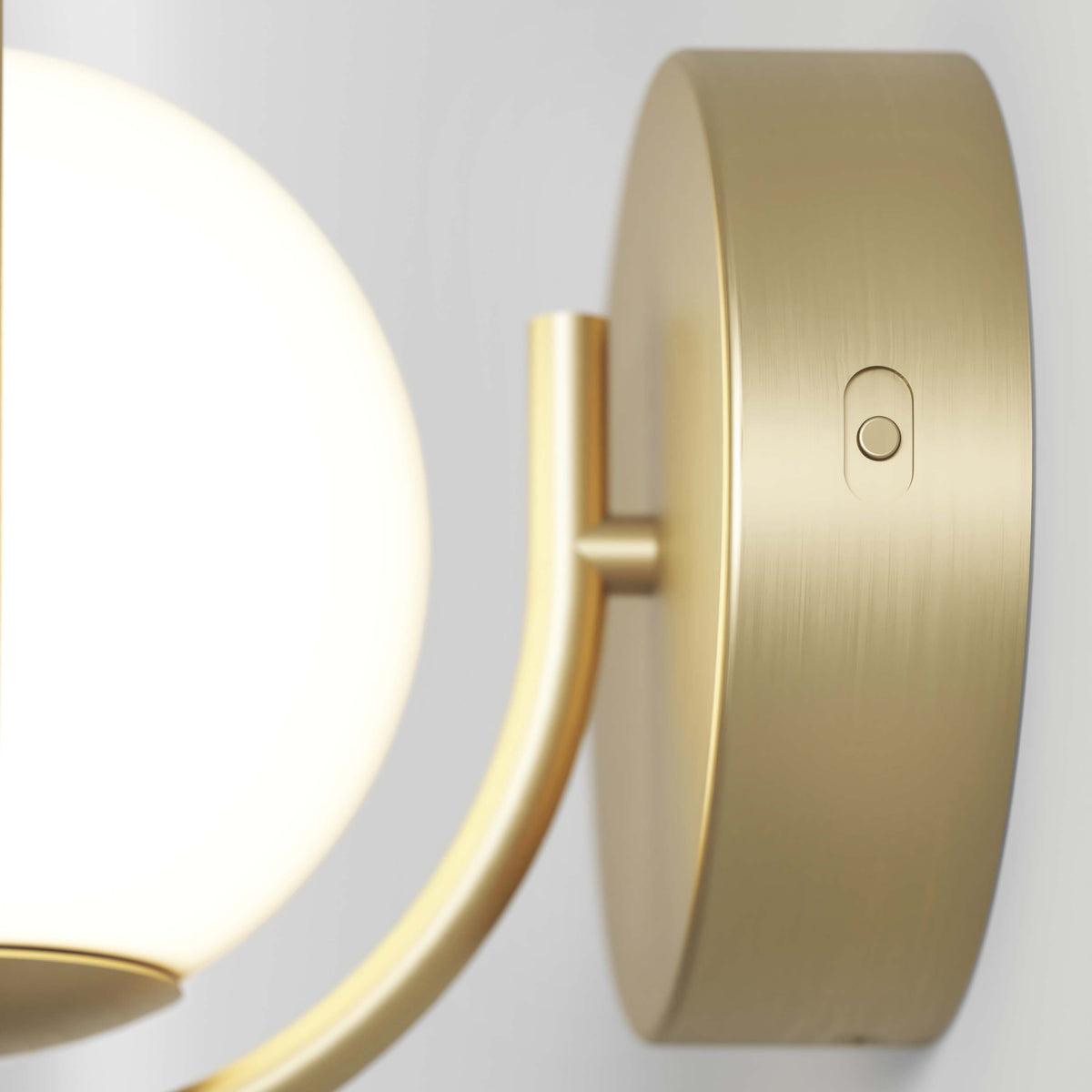 Close-up of the Artika Bloom LED Sconce 3 CCT, a modern brass wall fixture with a round frosted glass shade, circular base, and small button switch.