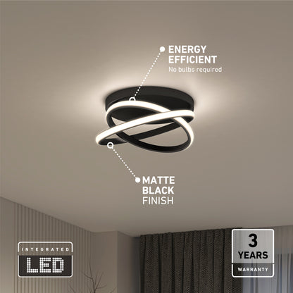The Orbia modern LED flush mount light 3 CCT by Artika features a matte black finish and curved design, installed on a white ceiling. Energy efficient, no bulbs required, and backed by a 3-year warranty. Dark curtains and a plant appear below.
