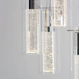 Close-up of modern pendant lights with cylindrical glass covers, featuring tiny bubbles and bright white LED illumination, giving a sparkling effect against a soft grey background.