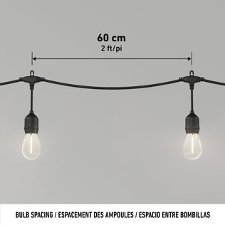 Two bulbs on the Artika Eclipse Solar String Light with Remote are shown on a black string, spaced 60 cm (2 ft) apart, with labeled measurement above. Text below reads: BULB SPACING / ESPACEMENT DES AMPOULES / ESPACIO ENTRE BOMBILLAS.