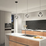 Modern kitchen with wood and white cabinetry, black herringbone backsplash, and three decorative pendant lights over a white island with a sink. A cutting board and utensils are on the counter.