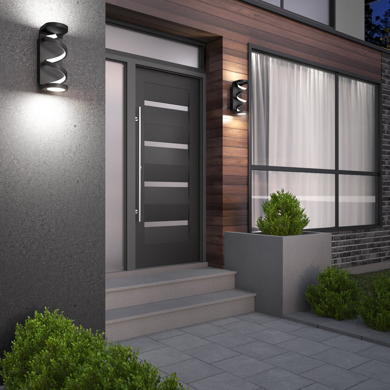 Modern house entrance featuring a gray front door, large window, wood and concrete exterior, potted plants, steps, tiled pathway, and Artikas Swirl indoor-outdoor LED wall lights illuminating the space in the evening.
