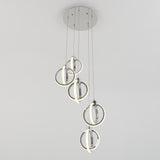 Modern ceiling light fixture with five circular LED rings hanging at different lengths from a round metallic base, against a plain white background.