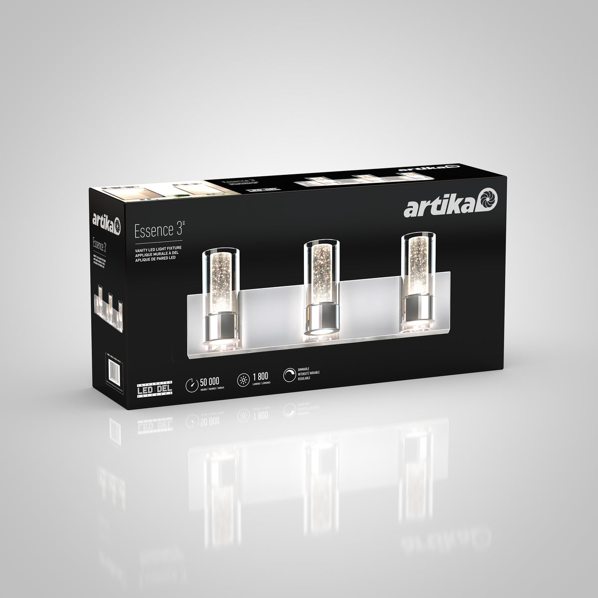 Black and white packaging box for an Artika Essence 3 vanity light fixture, featuring three lights with crystal details. The box shows product images, features, and icons for LED, brightness, and lifespan.