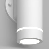 A modern cylindrical white wall light fixture with a subtle glowing ring near the top and a bright circular light at the base, attached to a round wall plate.